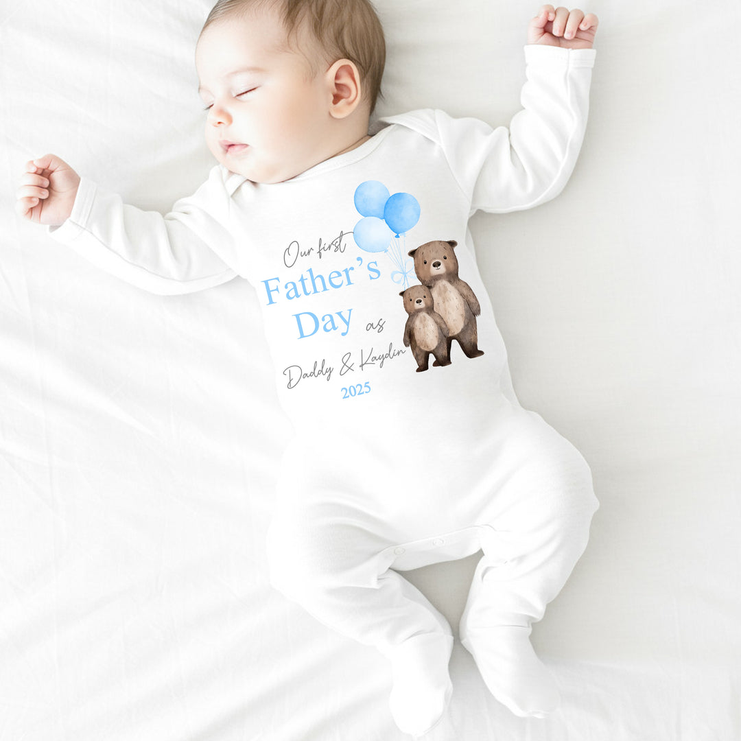 Personalised white Father's Day baby grow/sleepsuit that says 'Our First Father's Day as Daddy & Kaydin 2025'. This design features 2 brown bears holding 3 blue balloons