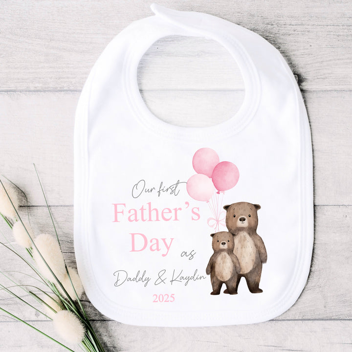 Personalised white Father's Day baby bib that says 'Our First Father's Day as Daddy & Kaydin 2025'. This design features 2 brown bears holding 3 pink balloons