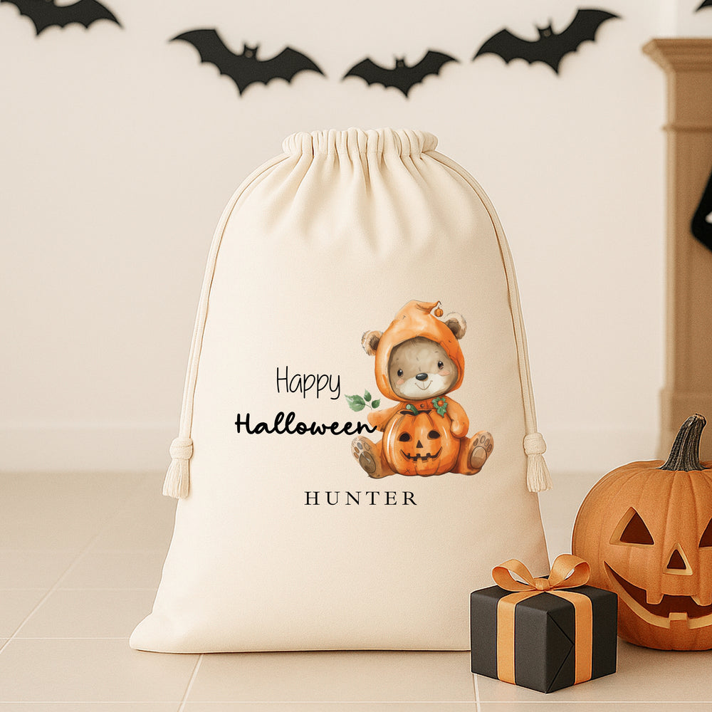 Halloween-themed drawstring bag with a teddy bear in a pumpkin costume, surrounded by pumpkins and gift boxes.