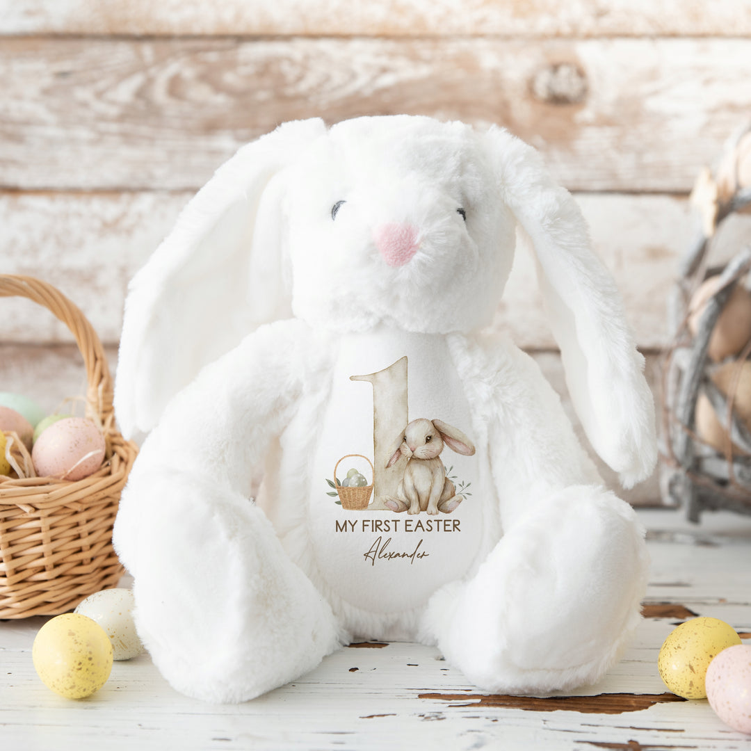 White Easter Teddy that says 'My First Easter Alexander'. This design features a big beige 1 with a beige rabbit and Easter basket next to it.