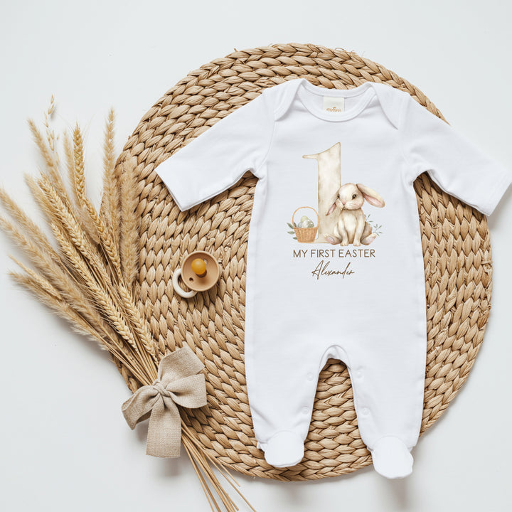 Personalised white Easter babygrow that says 'My First Easter Alexander'. This design features a big beige 1 and a brown rabbit and an Easter basket