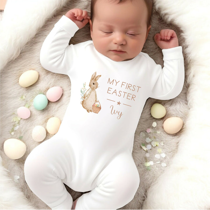 Personalised white Easter baby grow/sleepsuit that says 'My First Easter Ivy'. This design features a rabbit wearing a beige jacket 