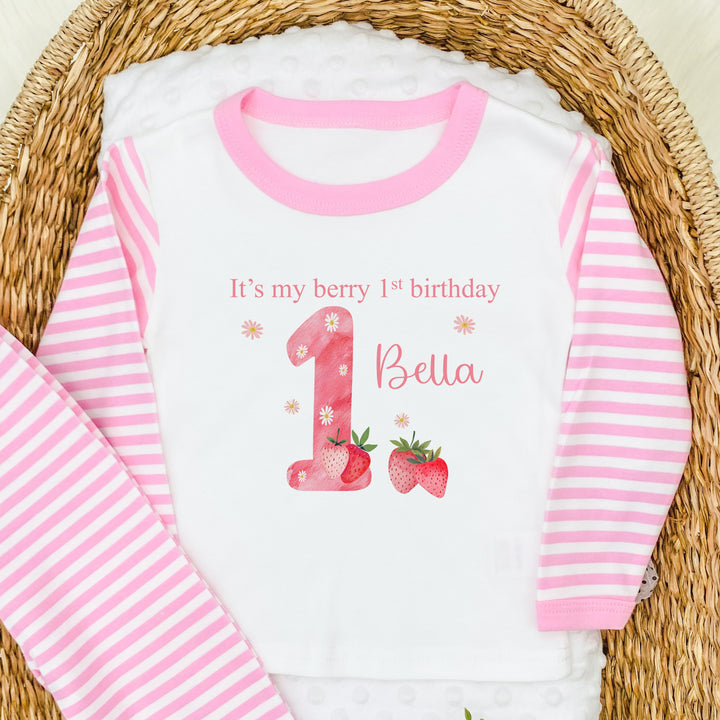 Personalised pink stripe pyjamas that say 'It's my berry 1st birthday 1 Bella' This design features a pink 1 with strawerrys around it 