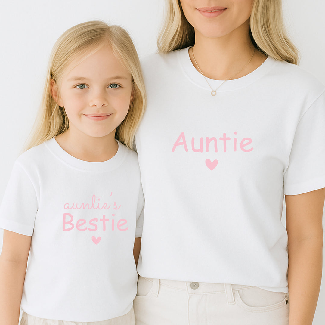 Woman and child wearing matching white t-shirts with pink text on a plain background