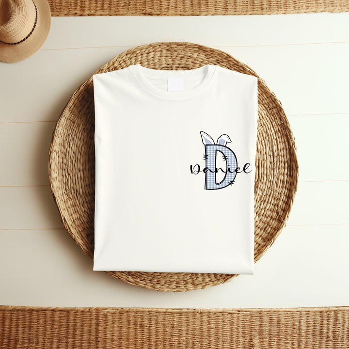 Personalised white Easter t-shirt that says 'D Daniel'. This design features a blue tartan D with blue bunny ears on it 