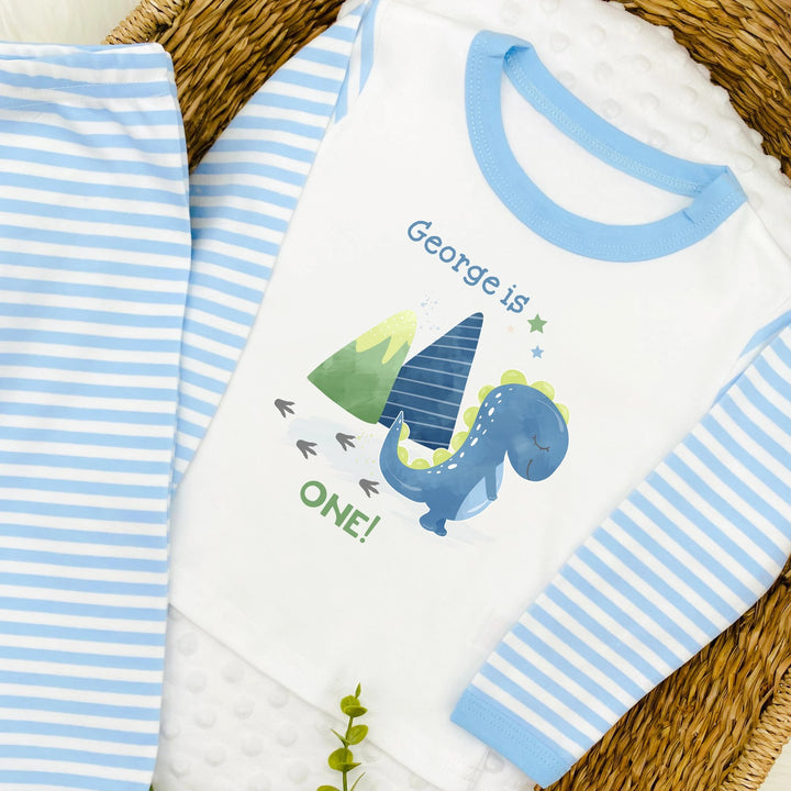 Blue Stripe birthday pyjamas that say 'George is ONE!'. This design features a blue dinosaur