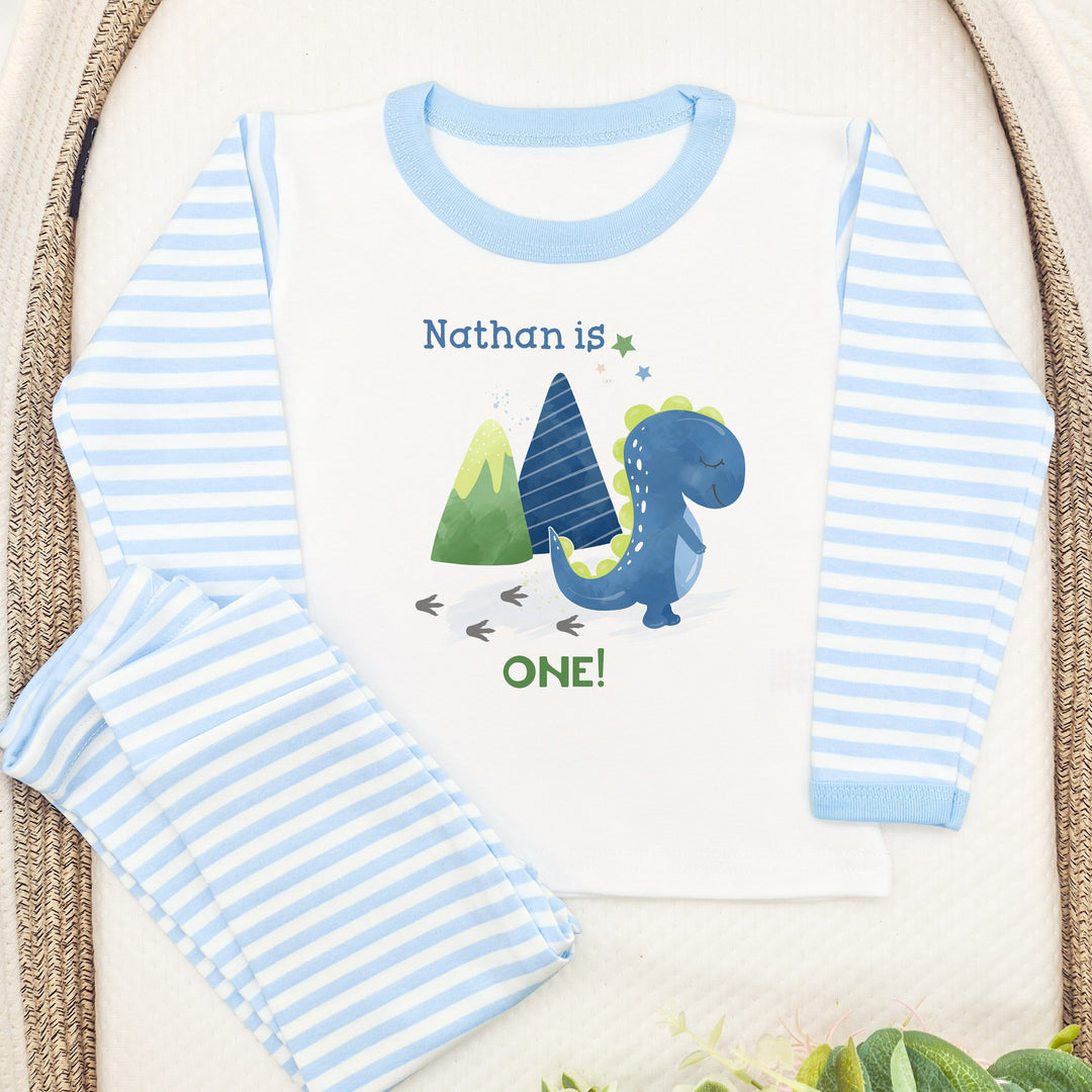 Blue Stripe birthday pyjamas that say 'Nathan is ONE!'. This design features a blue dinosaur