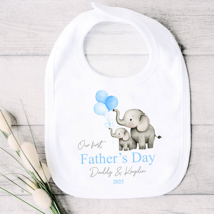 Personalised white Father's Day baby bib that says 'Our First Father's Day Daddy & Kaydin 2025'. This design features 2 grey elephants holding 3 blue balloons