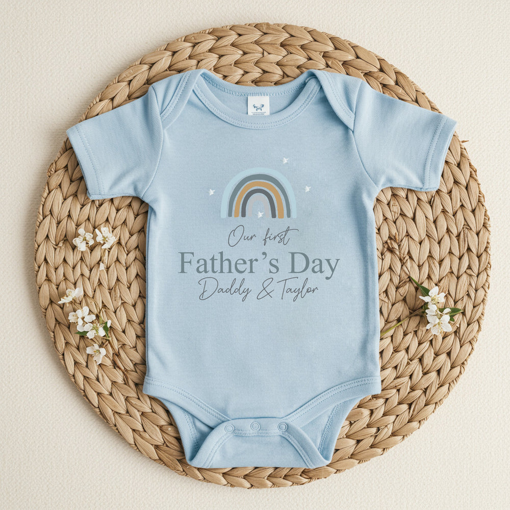 Personalised blue Father's Day baby vestthat says 'Our First Father's Day Daddy & Taylor'. This design features a blue rainbow 