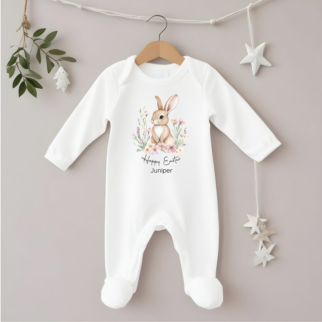 Personalised white Easter baby grow/sleepsuit that says 'Hoppy Easter Juniper'. This design features a brown bunny in a floral wreath