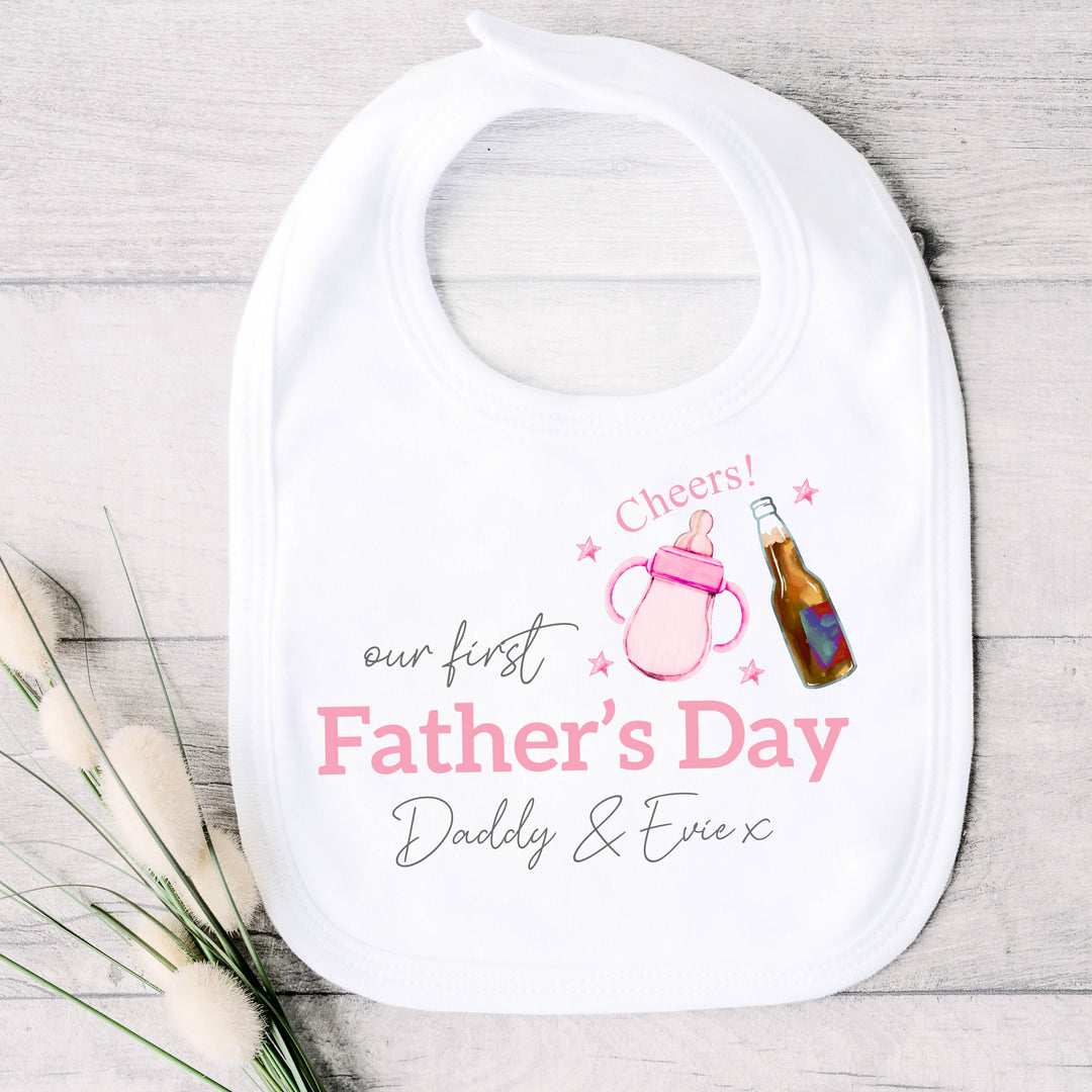 Personalised white Father's Day baby bib that says 'Our First Father's Day Daddy & Evie x'. This design features a pink bottle of milk with a bottle of beer