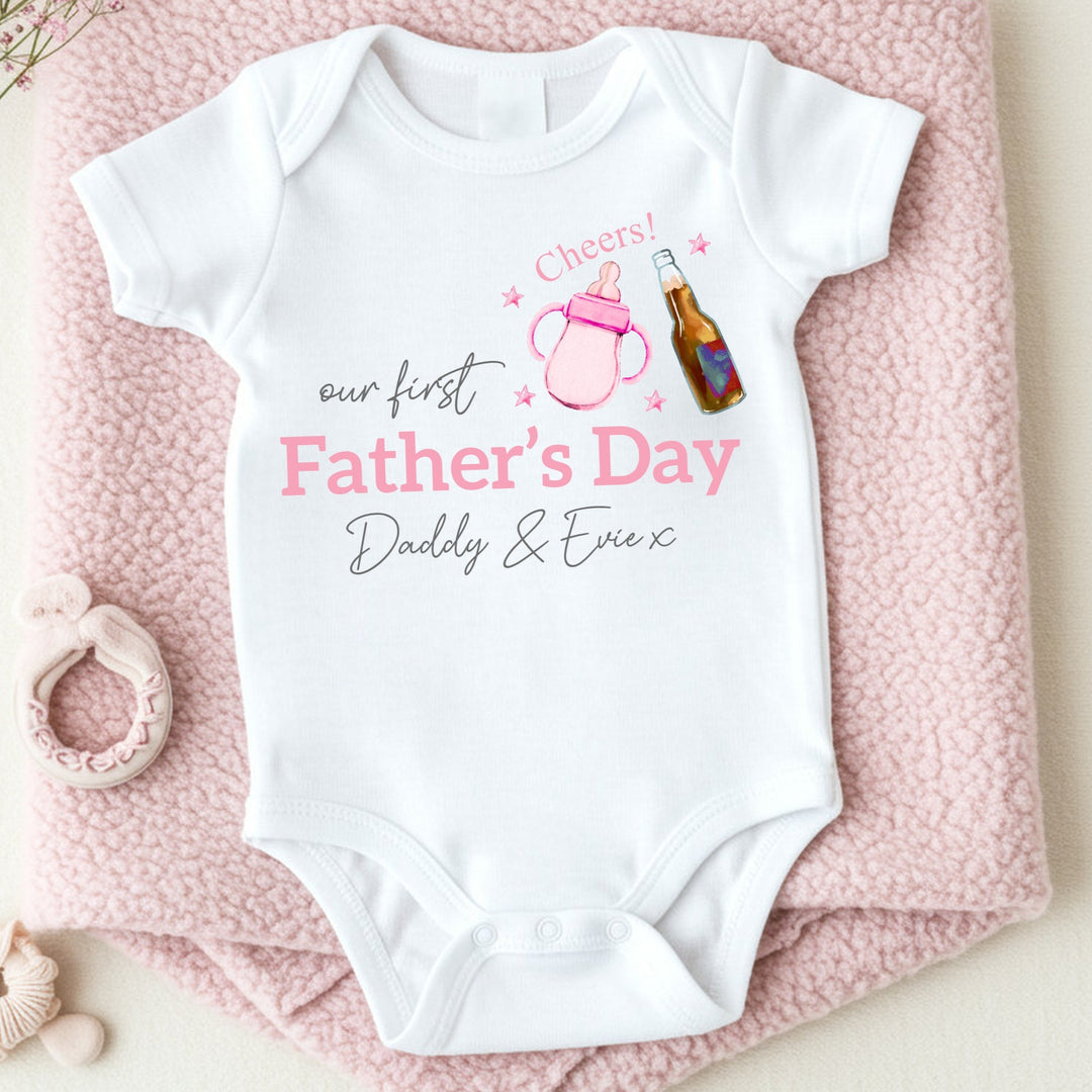 Personalised white Father's Day baby vest that says 'Our First Father's Day Daddy & Evie x'. This design features a pink bottle of milk with a bottle of beer