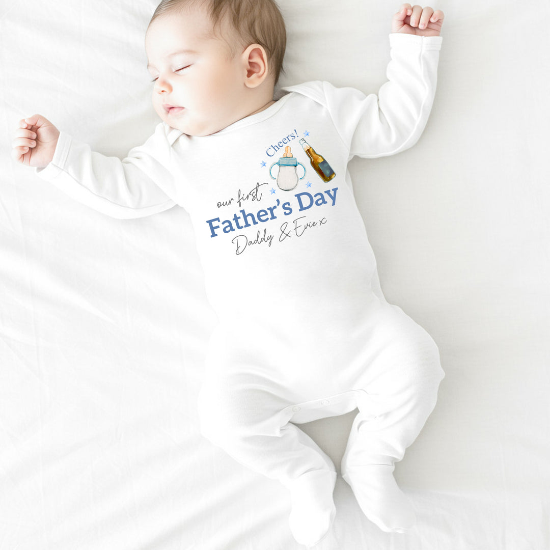 Personalised white Father's Day baby grow/sleepsuit that says 'Our First Father's Day Daddy & Evie x'. This design features a milk bottle and beer bottle saying 'Cheers' above it 