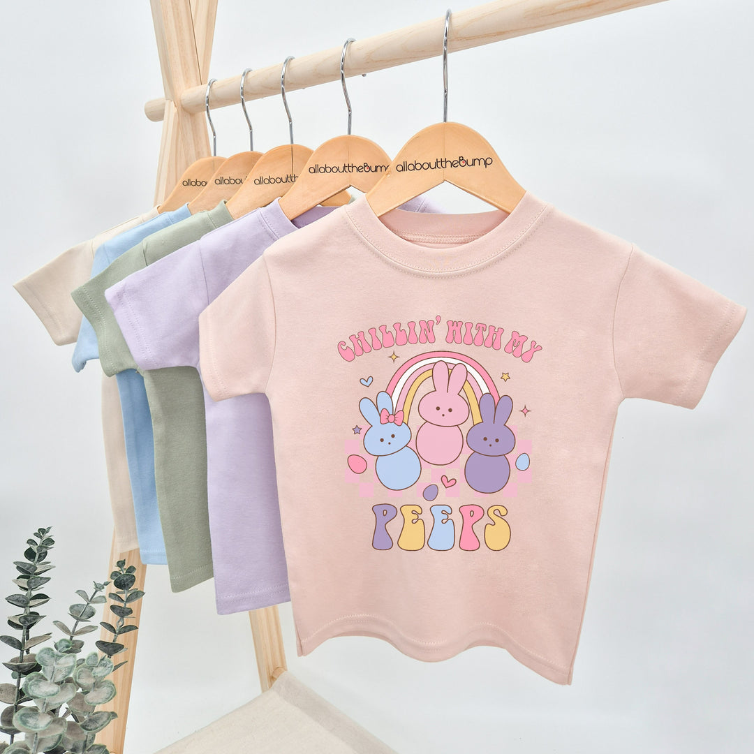 Baby Pink retro style Easter t-shirt that says 'Chillin' with my Peeps'. This design featuring 3 rabbits in front of a rainbow