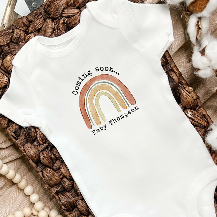 Baby announcement vests that says: 
Coming soon... Baby Thompson with a rainbow in the middle 