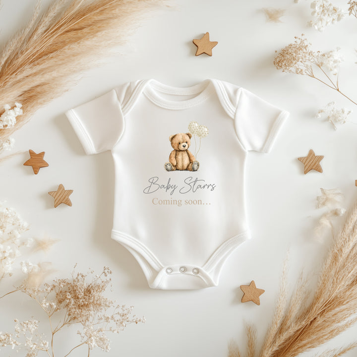 Baby announcement vests that says: 'Baby Starrs Coming soon...' with a brown bear holding balloons