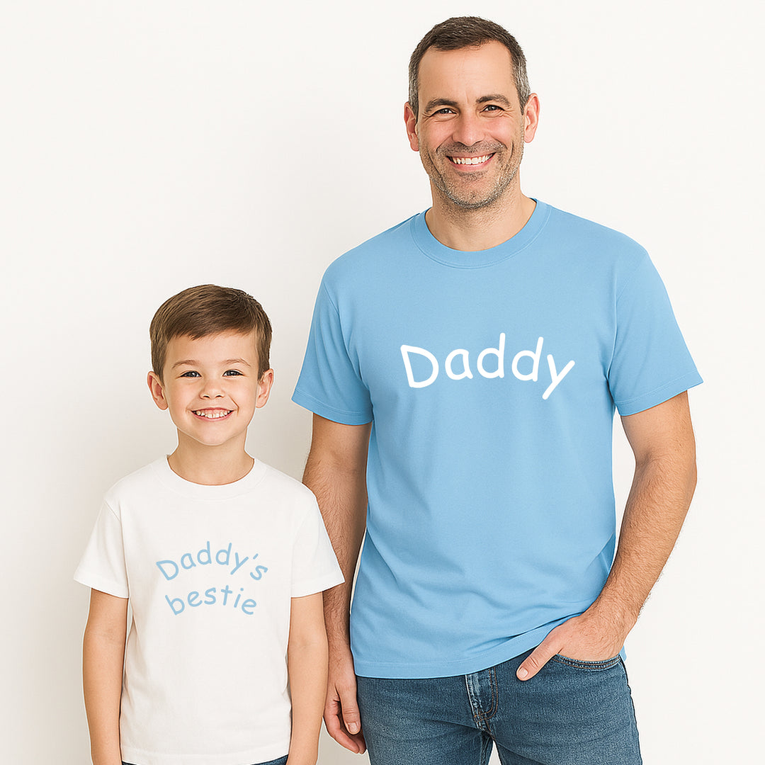 Man and child wearing matching 'Daddy' and 'Daddy's bestie' shirts on a plain background