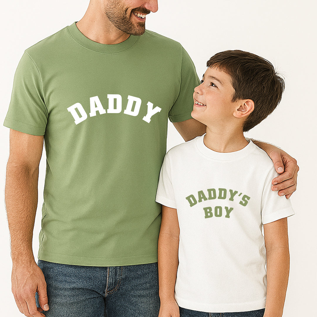 Man and child wearing matching shirts with 'DADDY' and 'DADDY'S BOY' text.