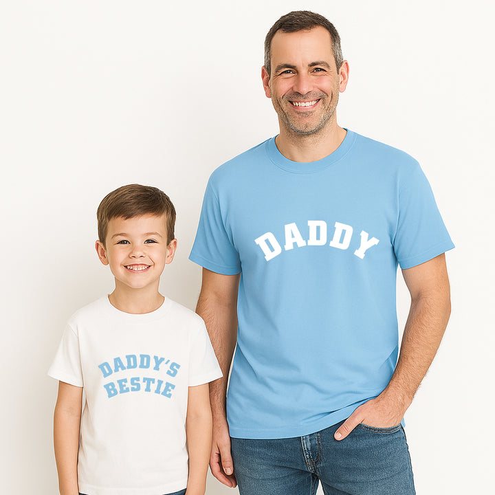 Man and child wearing matching 'DADDY' and 'DADDY'S BESTIE' shirts on a plain background