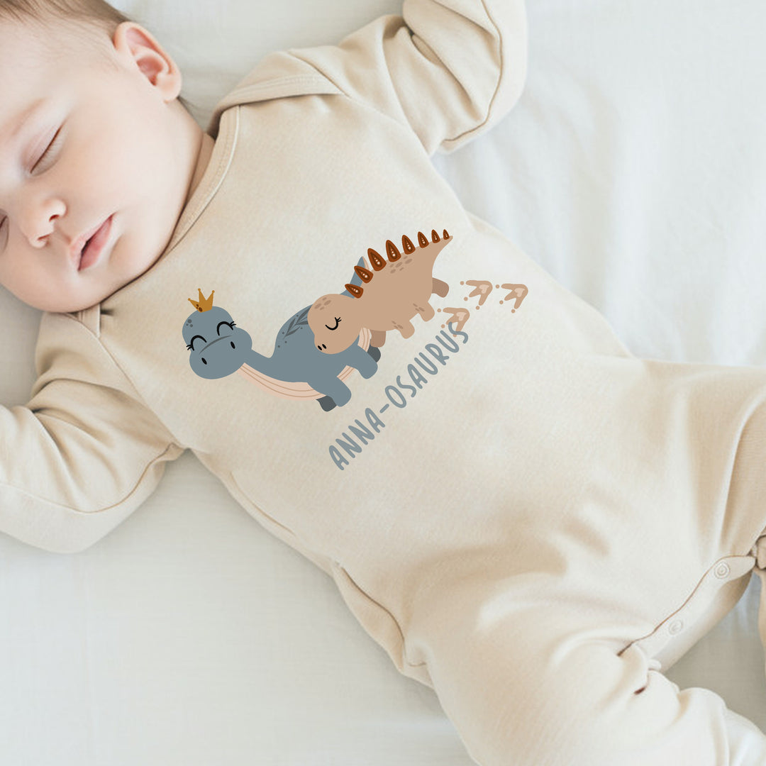 a personalised beige baby grow that says 'anna-osaurus'. This design features 2 dinosaurs