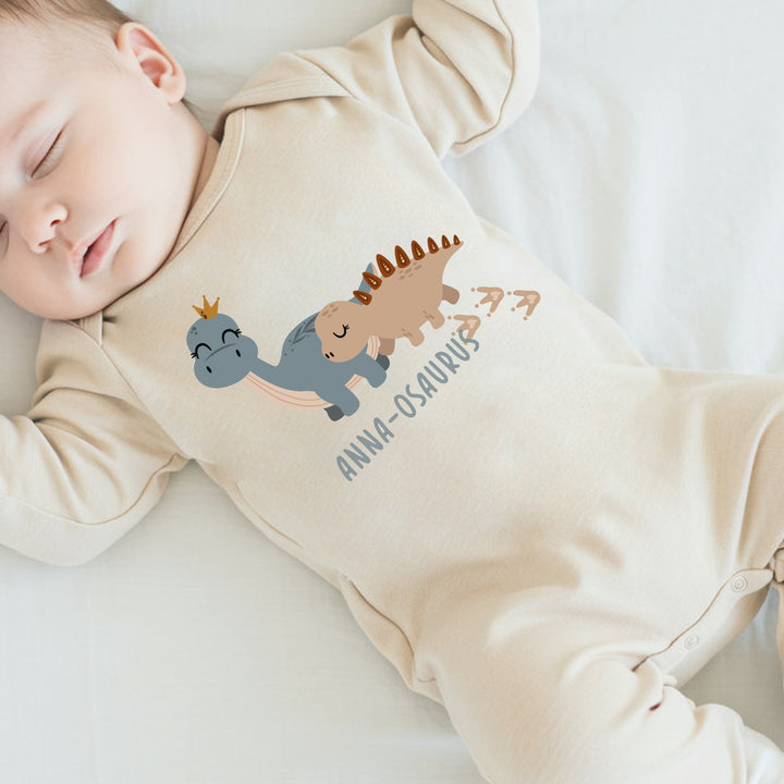 a personalised beige baby grow that says 'anna-osaurus'. This design features 2 dinosaurs