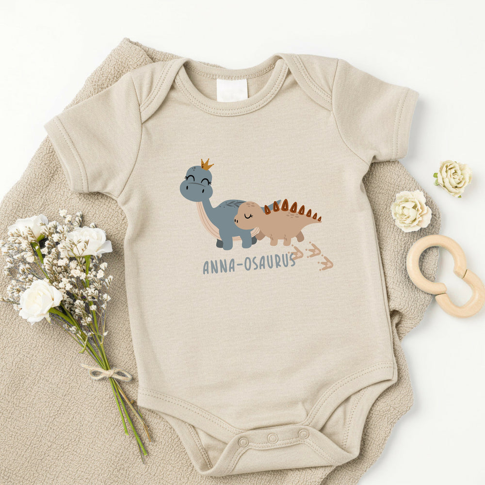 a personalised beige baby vest that says 'anna-osaurus'. This design features 2 dinosaurs