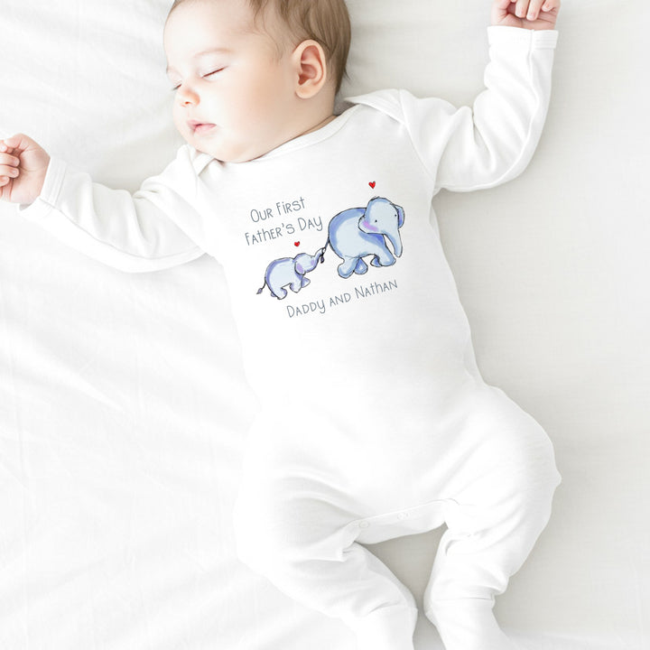 Personalised white Father's Day baby grow/sleepsuit that says 'Our First Father's Day Daddy and Nathan'. This design features 2 blue elephants