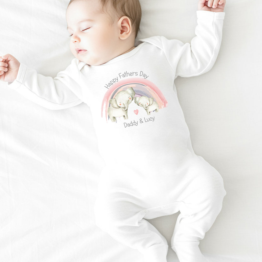 Personalised white Father's Day baby grow/sleepsuit that says 'Happy Fathers Day Daddy & Lucy'. This design features a pink rainbow with 2 elephants standing in the middle of it 