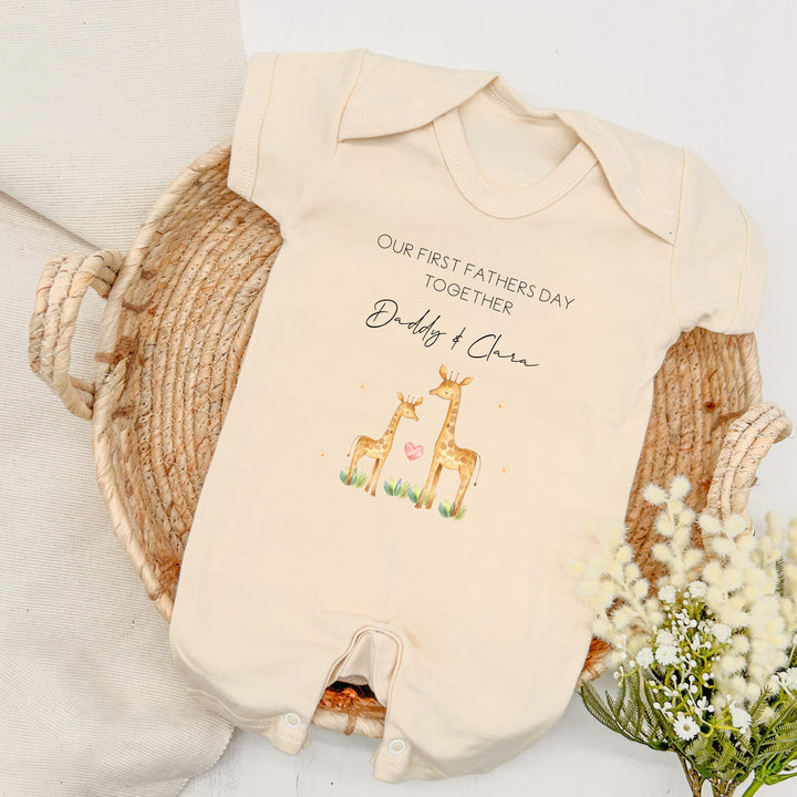 Personalised beige Father's Day baby romper that says 'Our First Father's Day Together Daddy & Clara'. This design features 2 giraffes