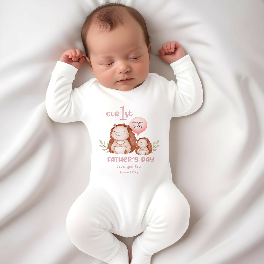 Personalised white Father's Day baby grow/sleepsuit that says 'Our 1st Father's Day love you lots from Ellie'. This design features 2 hedgehogs, one of which is holding a balloon that say 'Love you daddy'