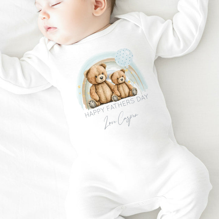 Personalised white Father's Day baby grow/sleepsuit that says 'Happy Father's Day Love Casper'. This design features a blue rainbow with 2 teddy bears sitting in the middle of it