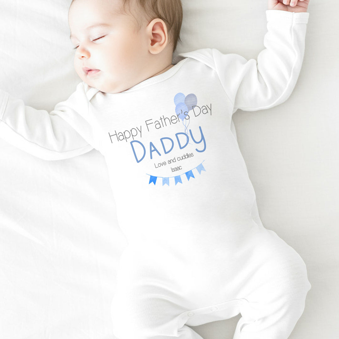 Personalised white Father's Day baby grow/sleepsuit that says 'Happy Father's Day Daddy Love and Cuddles Issac'. This design features blue banners and balloons