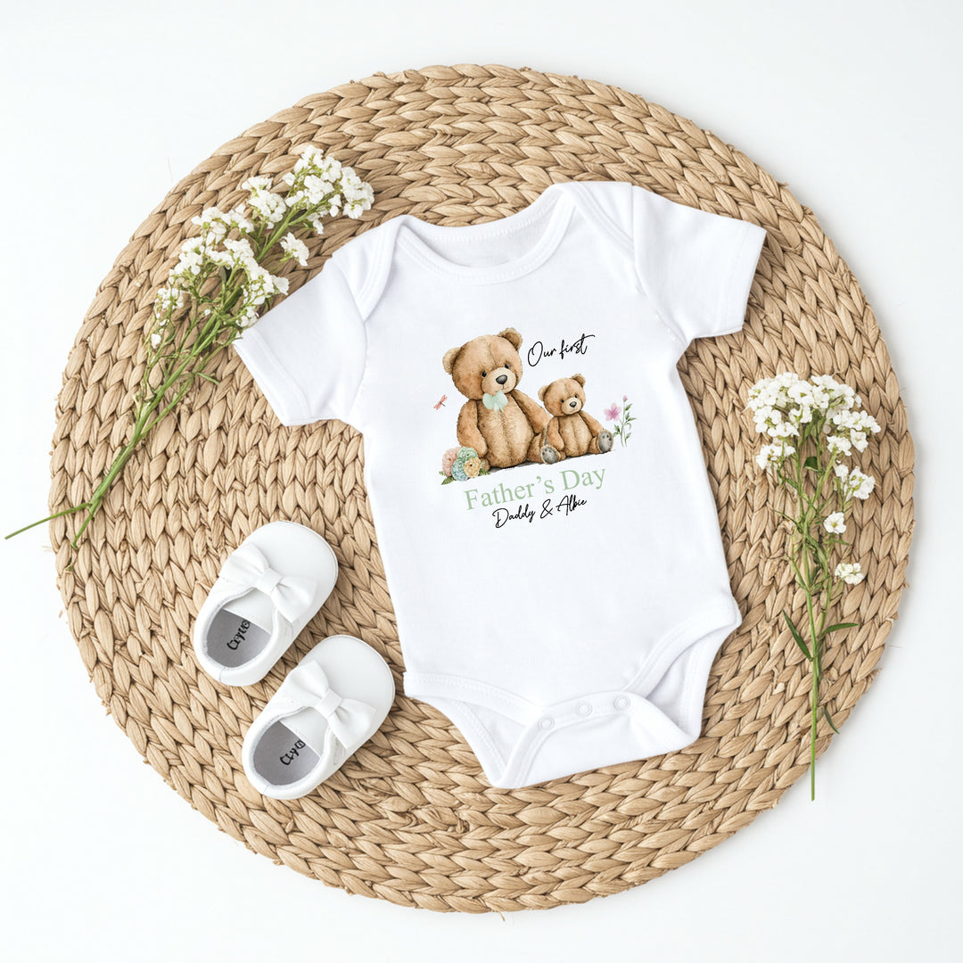 Personalised white Father's Day baby vest that says 'Our first Father's Day Daddy & Albie'. This design features a big teddy bear wearing a sage green bow tie sitting next to a little teddy bear