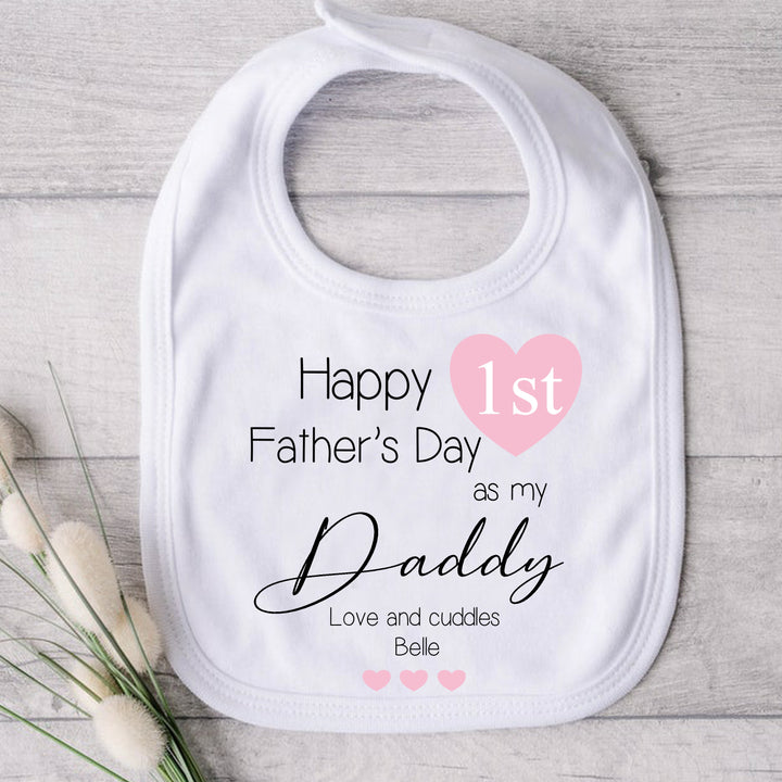 Personalised white Father's Day baby bib that says 'Happy 1st Father's Day as my Daddy Love and Cuddle Belle'. This design features a multiple pink hearts