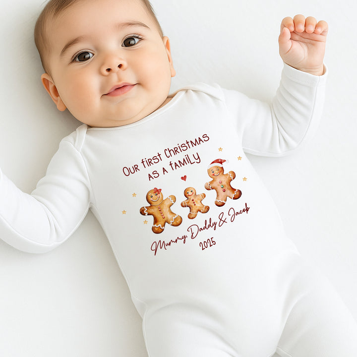 Baby wearing a white onesie with Christmas-themed text and gingerbread men graphics.