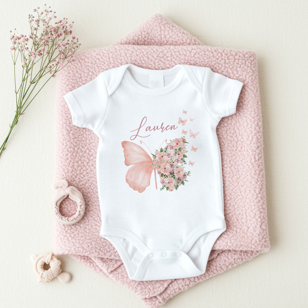 a personalised white baby vest that says 'Laney'. This design features a butterfly with flowers next to it