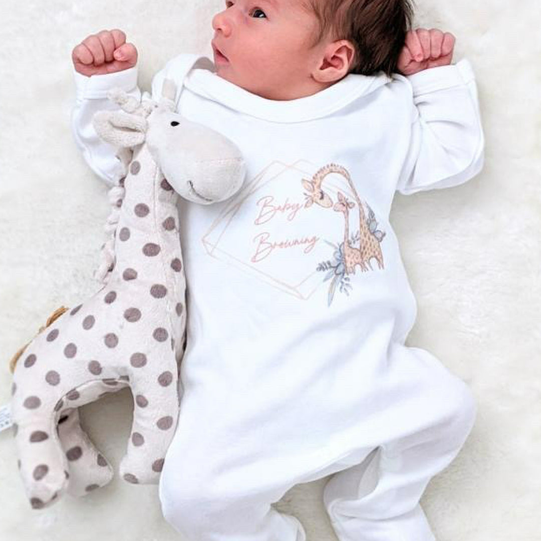 A white babygrow printed with a wreath design. There is a family of giraffes on the design and the wreath can be personalised with a choice of name.