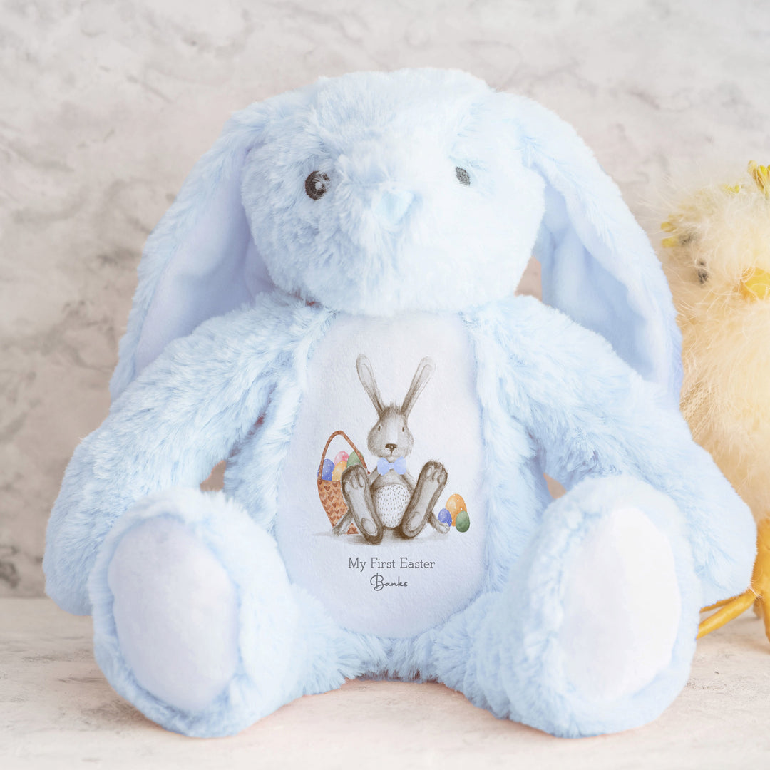 Personalised Blue bunny Easter teddy saying 'My First Easter Banks'. This design features a grey bunny wearing a blue bow tie and a basket filled with Easter eggs