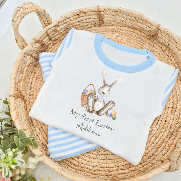 Personalised blue stripe Easter pyjamas that say 'My First Easter Addison'. This design features a grey rabbit wearing a blue bowtie surrounded by easter eggs