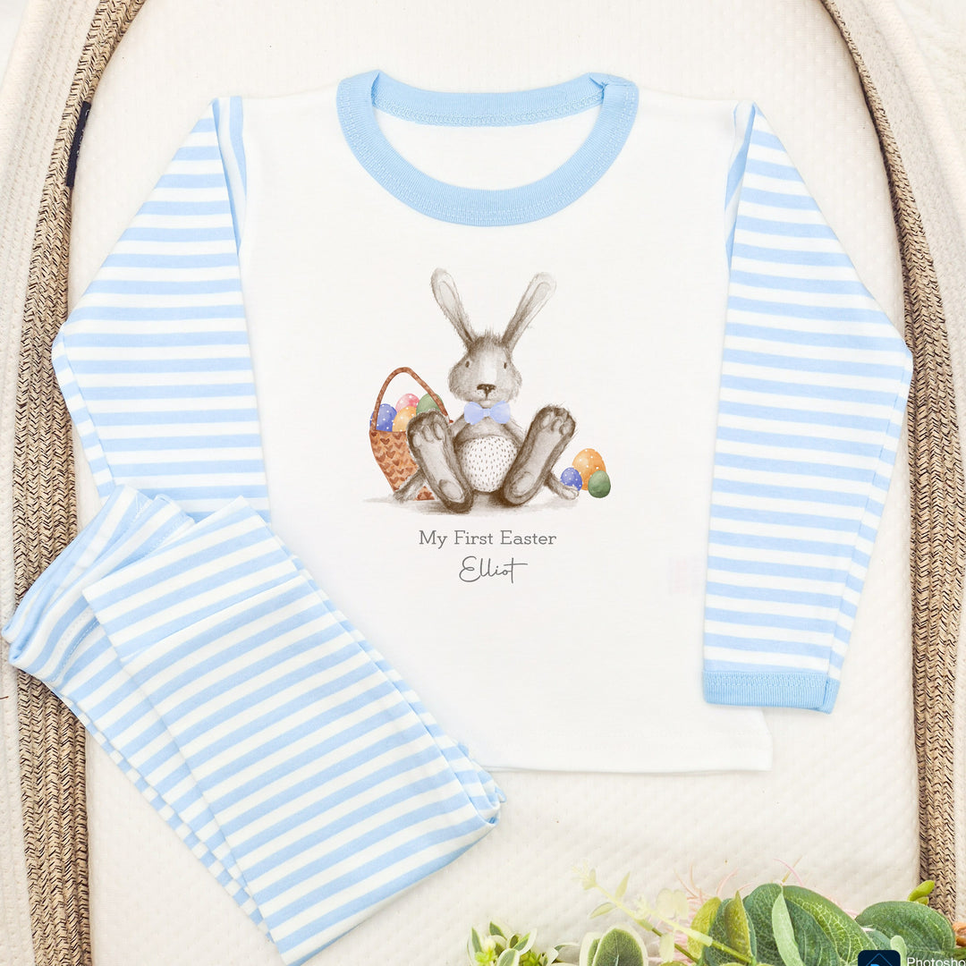 Personalised blue stripe Easter pyjamas that say 'My First Easter Elliot'. This design features a grey rabbit wearing a blue bowtie surrounded by easter eggs