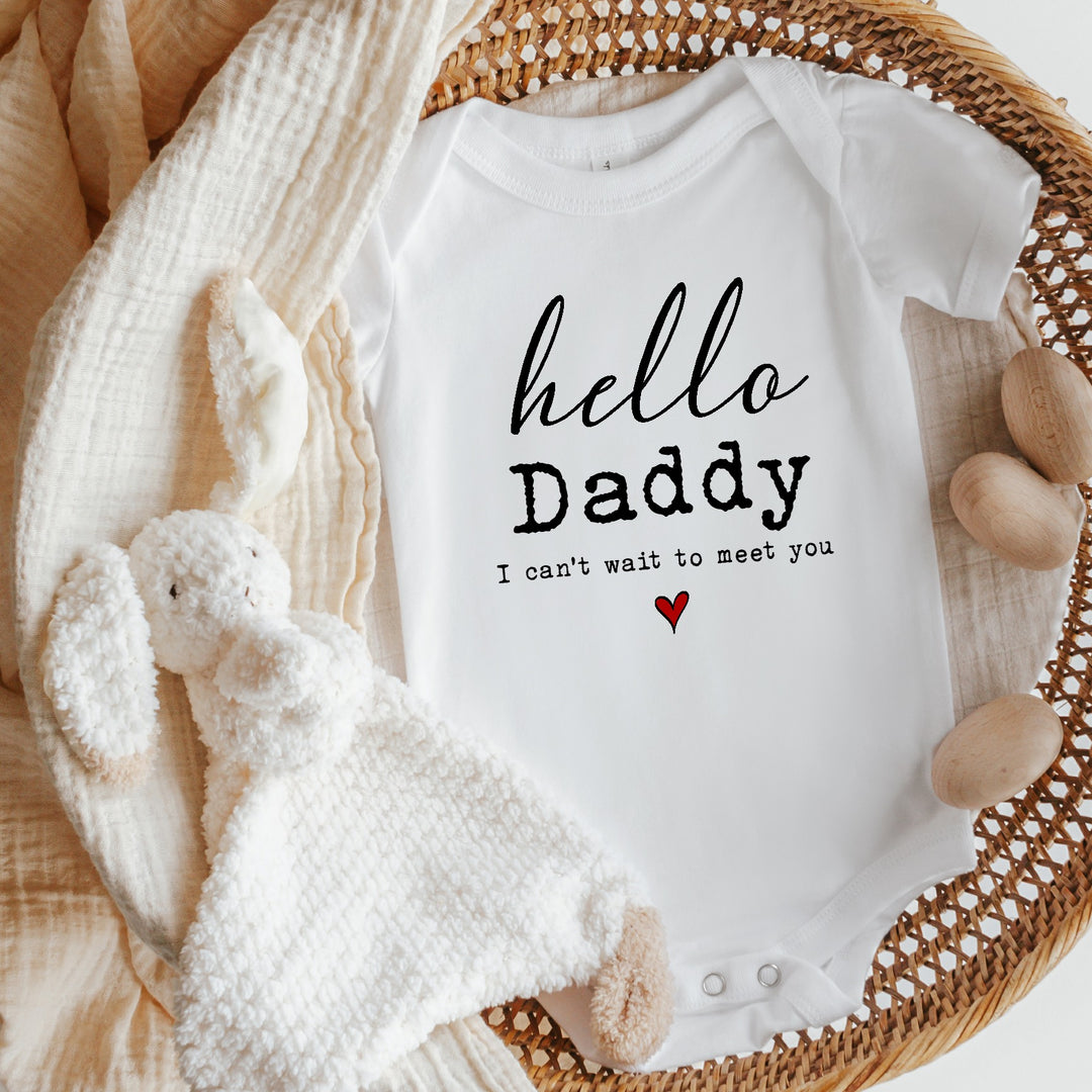 Baby announcement vests that says: 'hello Daddy I can't wait to meet you' with a red heart underneath the text