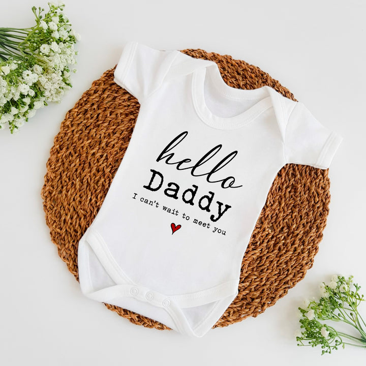 Baby announcement vests that says: 'hello Daddy I can't wait to meet you' with a red heart underneath the text