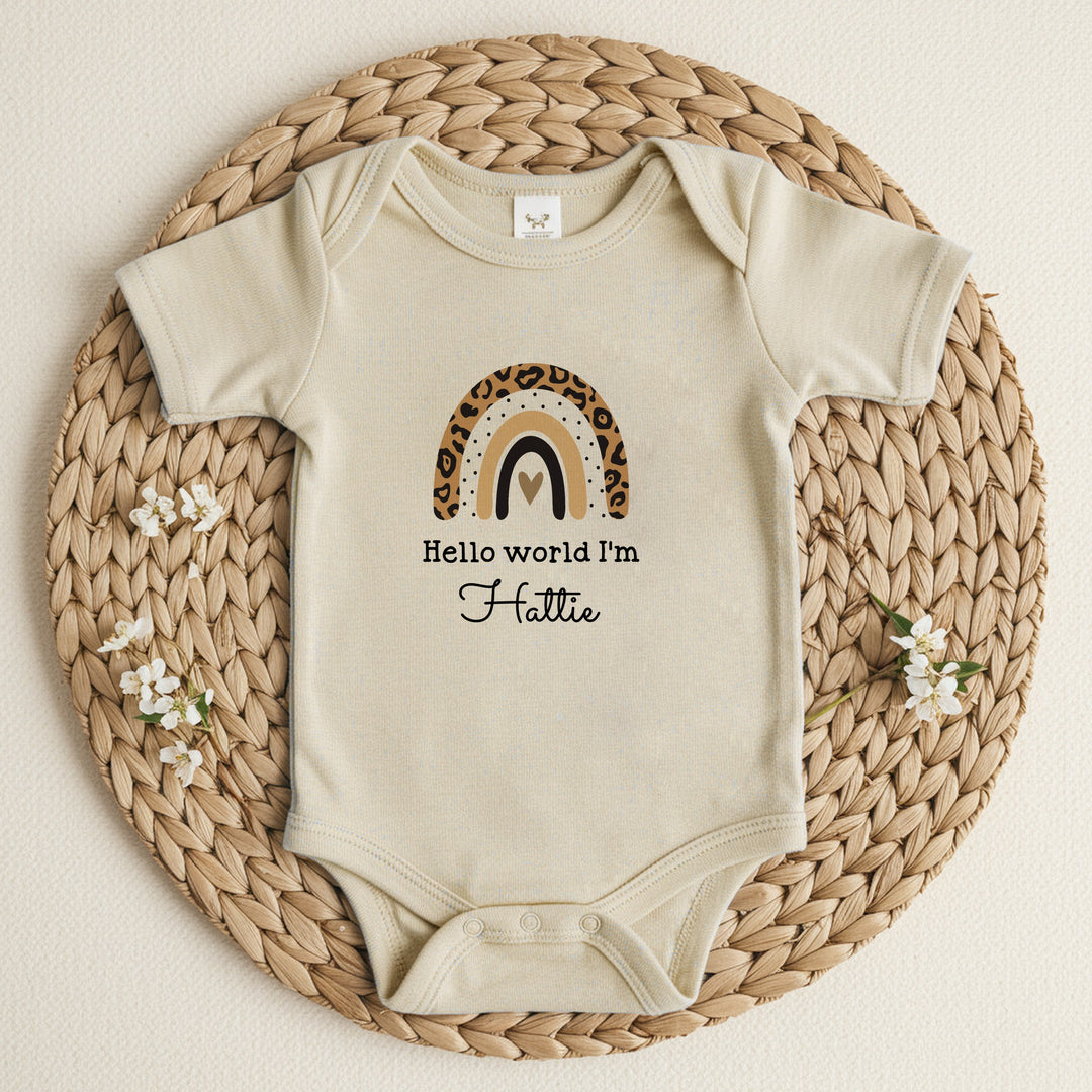 a personalised beige baby growvest that says 'Hello World I'm Hattie'. This design features a leopard print rainbow