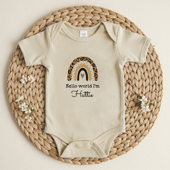 a personalised beige baby growvest that says 'Hello World I'm Hattie'. This design features a leopard print rainbow