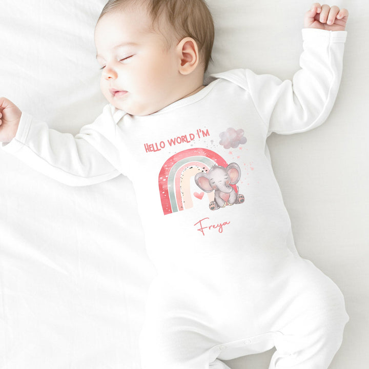 personalised white baby grow that says 'Hello world I'm Freya'. This design features a pink rainbow with an elephant sitting in front of it