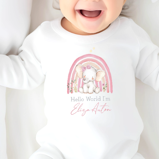 A babygrow printed with a pink rainbow and a baby elephant wearing a bow. The text says "Hello world I'm..." and can be personalised with a name of your choice.