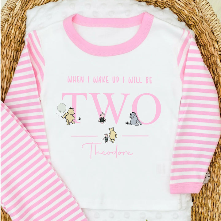 Personalised Pink stripe pyjamas that say 'When I wake up I will be TWO Theodore'. This design features the Classic Winnie the Pooh, Piglet and Eyore