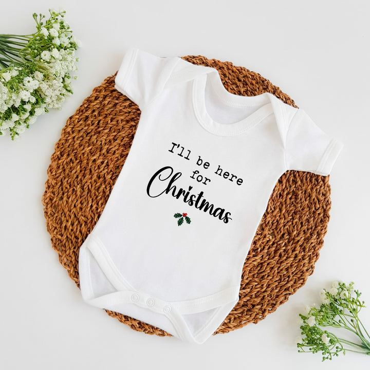 Baby announcement vests that says: I'll be home for Christmas with holly under