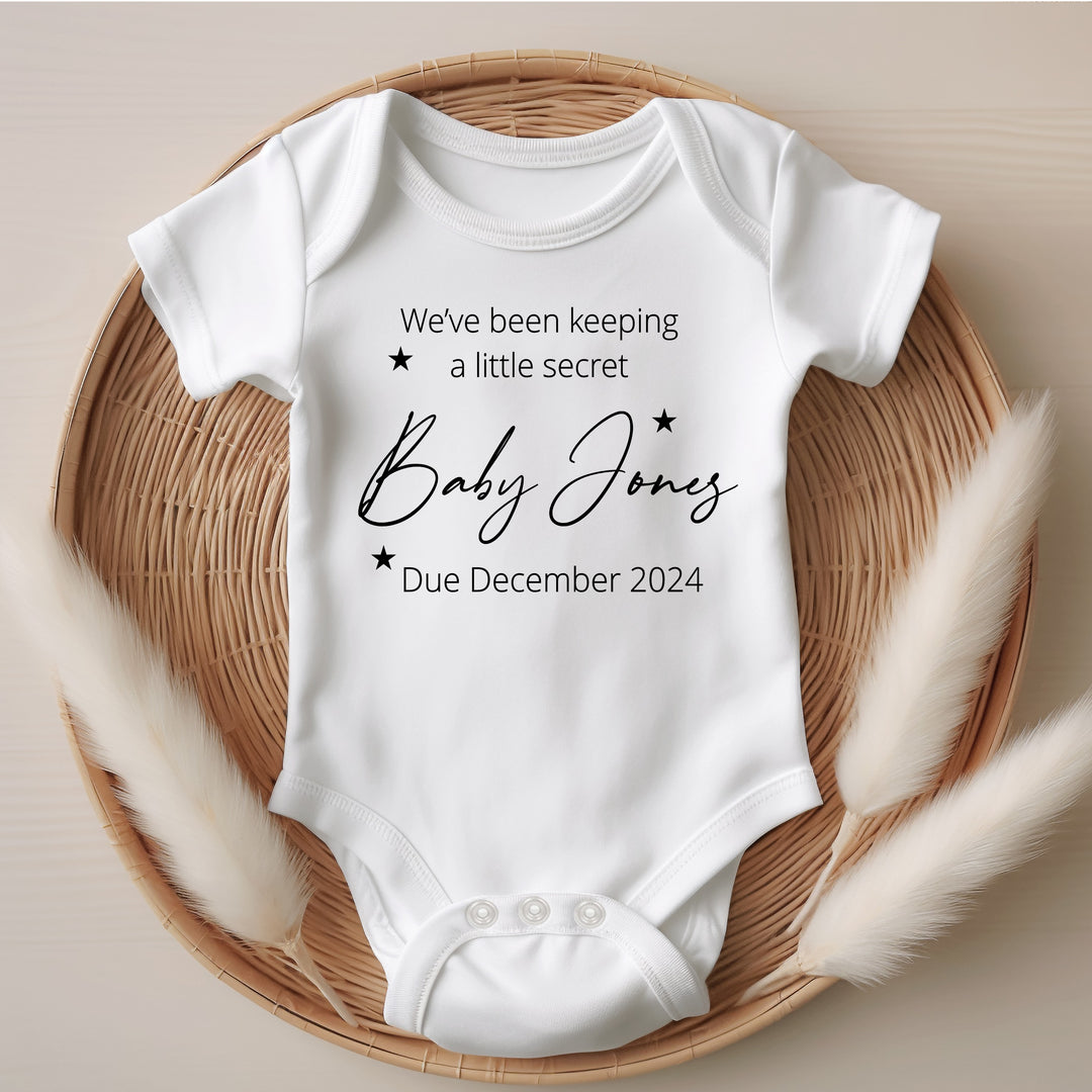 Baby announcement vests that says: We've been keeping a little secret Baby Jones Due December 2024 