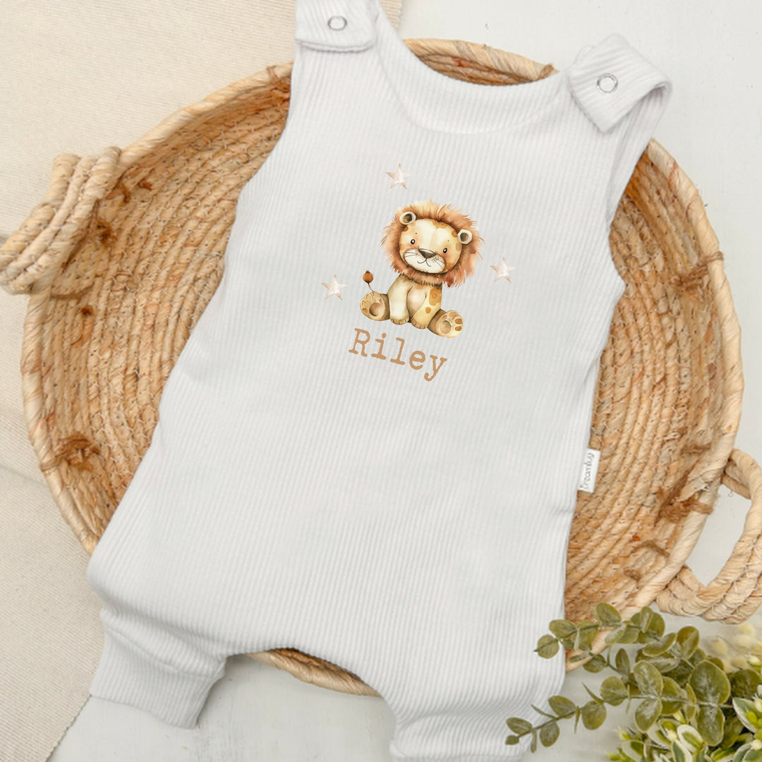 Personalised white ribbed dungarees that say 'Riley'. This design features a lion surrounded by stars